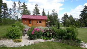 a small wooden cabin in a garden with flowers at Männiste Holiday Home in Hiievälja