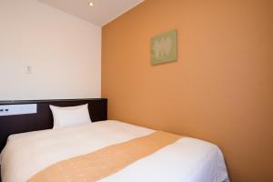 - une chambre avec un lit blanc et un mur orange dans l'établissement Chisun Hotel Utsunomiya, à Utsunomiya