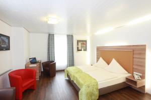 um quarto de hotel com uma cama e uma cadeira vermelha em Hotel Hubertus em Ennigerloh