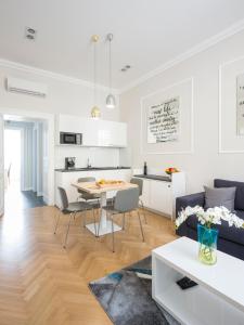 ein Wohnzimmer und eine Küche mit einem Tisch und einem Sofa in der Unterkunft White Rose Apartment in Zagreb