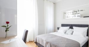 a white bedroom with a bed and a table at White Rose Apartment in Zagreb