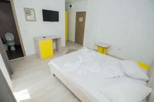 1 dormitorio con 1 cama blanca y TV en Glam Boutique Hotel, en Eforie Nord