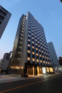 a tall building on a city street at night at Just Inn Premium Nagoya Station in Nagoya