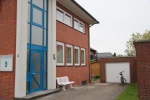 una bicicleta estacionada junto a un edificio de ladrillo con una puerta azul en Ferienwohnung Am Anker in Bislich, en Wesel