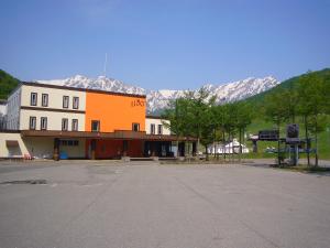 an empty parking lot in front of a building with mountains at Kashimayari Sports Village in Omachi