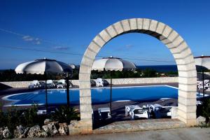 een zwembad met een boog en parasols bij Villa Hibiscus in Vieste