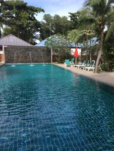 une grande piscine bleue avec des chaises et un mur dans l'établissement Marina Villa, à Lamai