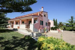 een roze huis met een veranda en een tuin bij Villa Hibiscus in Vieste