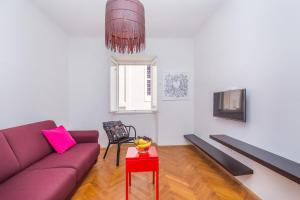 ein Wohnzimmer mit einem lila Sofa und einem roten Tisch in der Unterkunft Apartment Dox in Dubrovnik