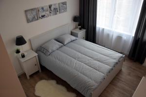 a bedroom with a white bed with two night stands and a window at Apartament Zawiszy Czarnego 10 in Koszalin