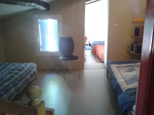 Cette chambre dispose de deux lits, d'une chaise et d'une fenêtre. dans l'établissement LA MAISON D'A COTE, à Montarnaud