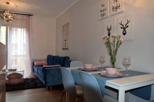 a living room with a table with chairs and a blue couch at Apartament Zawiszy Czarnego 10 in Koszalin
