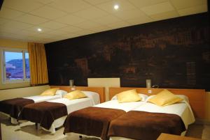 three beds in a room with a painting on the wall at Guilleumes Montserrat in Monistrol