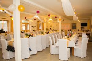 a banquet hall with white tables and chairs and balloons at Akácliget Vendégház és Major in Ófehértó