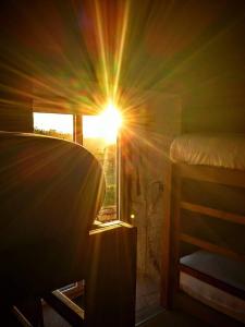 um quarto com uma cama e uma janela com o sol em Albergue Casa do Sardão em Carreço