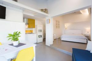a white bedroom with a bed and a kitchen at Marina Loft Sicily in Marina di Ragusa