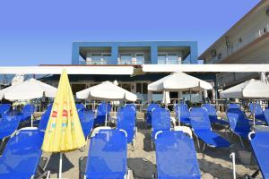 a group of blue chairs and umbrellas in front of a building at Megkas Theodoros in Paralia Katerinis