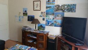 a living room with a television and a wall with pictures at Gîtes sains Baie du mont saint Michel LES HORTENSIAS in Sains