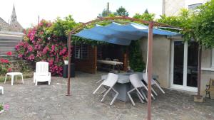 - une table et des chaises sous un parasol sur la terrasse dans l'établissement Gîtes sains Baie du mont saint Michel LES HORTENSIAS, à Sains