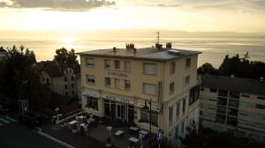 un edificio con la puesta de sol al fondo en Hôtel Evian Express - Terminus, en Évian-les-Bains