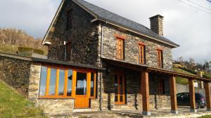 ein Steinhaus mit orangefarbenen Türen und Fenstern in der Unterkunft Casa con encanto in Cedeira