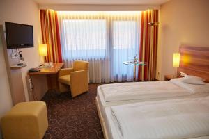 una camera d'albergo con letto, scrivania e TV di Flair Hotel Weinstube Lochner a Bad Mergentheim