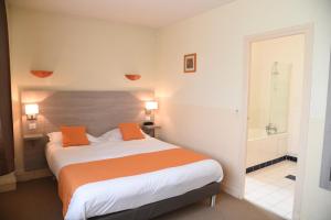 een slaapkamer met een bed met oranje kussens en een badkamer bij Hôtel Continental in Vierzon