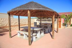 a pavilion with picnic tables and a straw umbrella at Peoples Park in Coral Bay