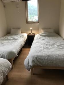 deux lits jumeaux dans une chambre avec fenêtre dans l'établissement Koko, à Fujikawaguchiko