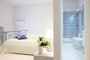 a white bedroom with a bed and a bathroom at Palazzo d'Auria ApartHotel in Naples
