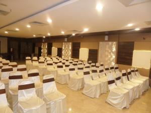 una sala banchetti con tavoli e sedie bianchi di Hotel Raj Palace a Ahmadnagar
