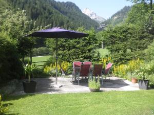 a group of chairs and an umbrella in a garden at Ferienhaus Regina in Werfenweng