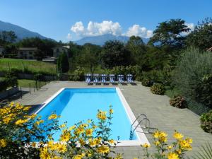 a swimming pool with chairs and mountains in the background at Residence Girasole Casa Gialla in Colico