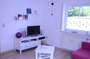 Malborn的住宿－Ferienwohnung Hunsrücknest，一间客厅,在白色的橱柜上配有电视