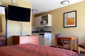 a bedroom with a bed and a table and a kitchen at Stay Inn & Suites - Stockbridge in Stockbridge