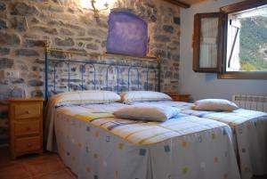 two beds in a room with a stone wall at Apartamento el Patio Casa Cajal in Torla