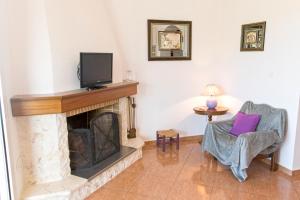 a living room with a fireplace with a tv and a chair at Ortaki Traditional House in Loúlos