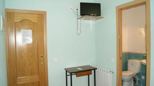 a bathroom with a toilet and a television on the wall at Casa Huésped Magdalena in Madrid