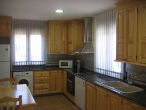 cocina con armarios de madera y microondas blanco en Casa rural Marcelina, en Beteta