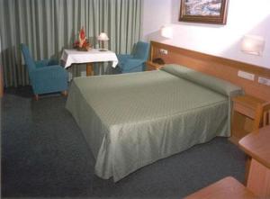 Habitación con cama, 2 sillas y lavabo. en Hotel San Vicente en Santiago de Compostela