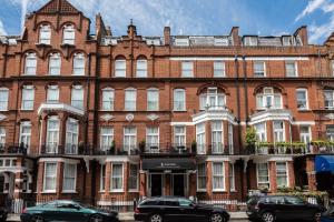 a large brick building with cars parked in front of it at Presidential Apartments Kensington in London