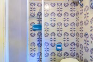 a bathroom with blue and white wallpaper and a toilet at Appartamento Arancio in Procchio +7 photos