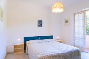 a white bedroom with a bed and a chandelier at Appartamento Arancio in Procchio