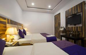 um quarto de hotel com duas camas e uma televisão de ecrã plano em Hotel Shri Vinayak at New Delhi Railway Station-By RCG Hotels em Nova Deli