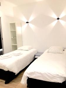 two beds in a room with white walls at Appartements Urban et Pure in Cannes