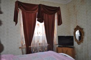 1 dormitorio con ventana, cama y espejo en Guest House Cico, en Telavi