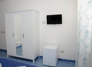 Habitación con armario blanco y TV en la pared. en Aurora B&B en Agropoli