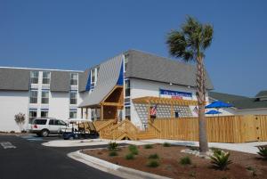 a hotel with a palm tree in front of a building at Outer Banks Inn in Kill Devil Hills