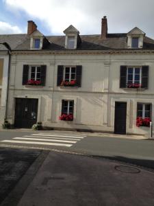 un edificio blanco con flores rojas en las ventanas en Le Chaton Rouge, en Saint-Pierre-du-Lorouër