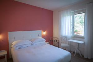 a bedroom with a white bed and a window at Arli Hotel Hideaway Punta Ala - Adults Only in Punta Ala